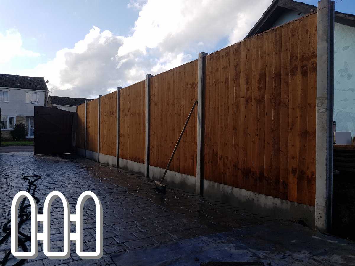 New wooden fence installation in residential area with wet cobblestone pavement and open gate, showcasing robust privacy and security enhancements.