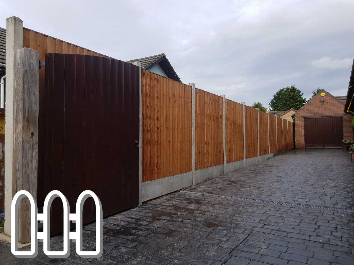 Long wooden fence with a dark brown gate installed on a cobblestone pavement, demonstrating residential fencing solutions by Fencing Colchester