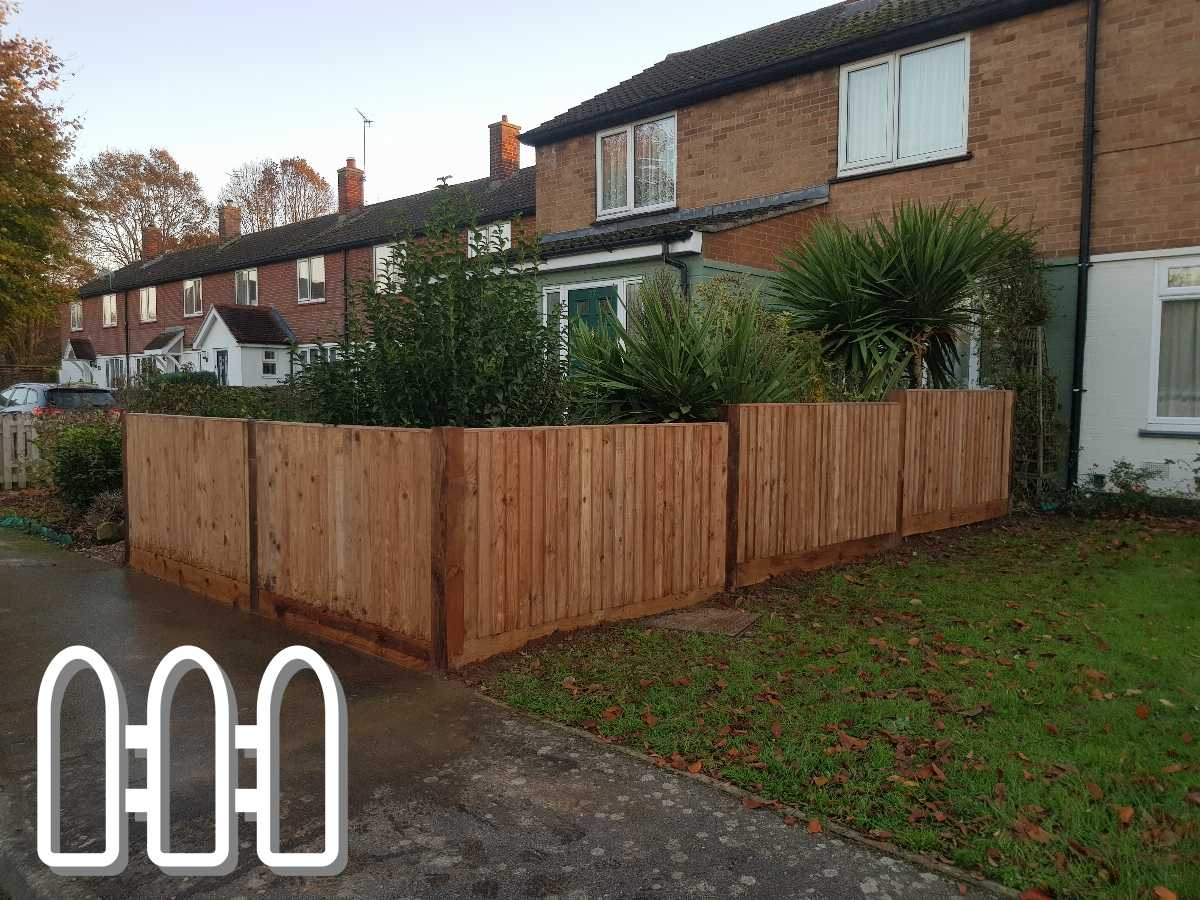 New wooden fencing installed around a residential property with tropical plants and row houses in the background