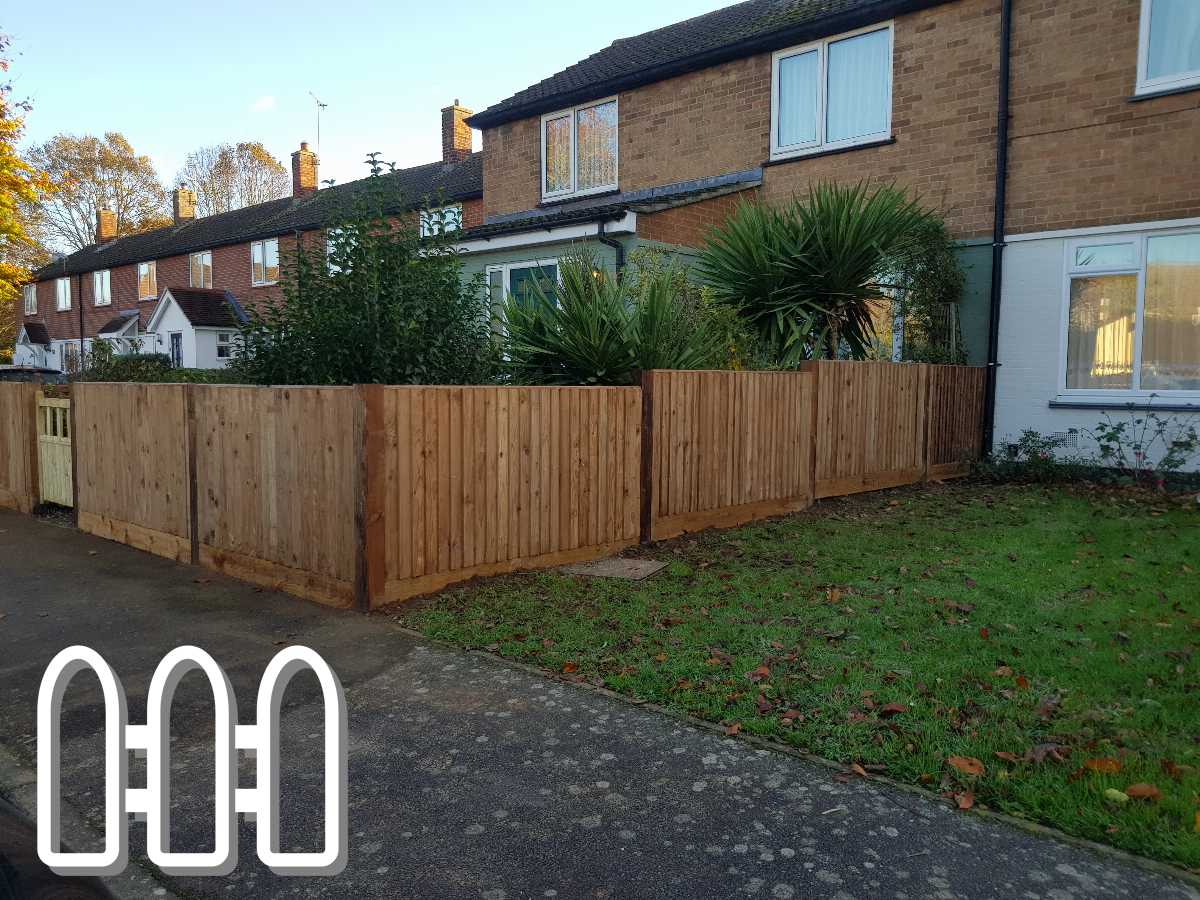 Newly installed wooden fence with vertical panels enhancing the front yard of a brick house with lush greenery.