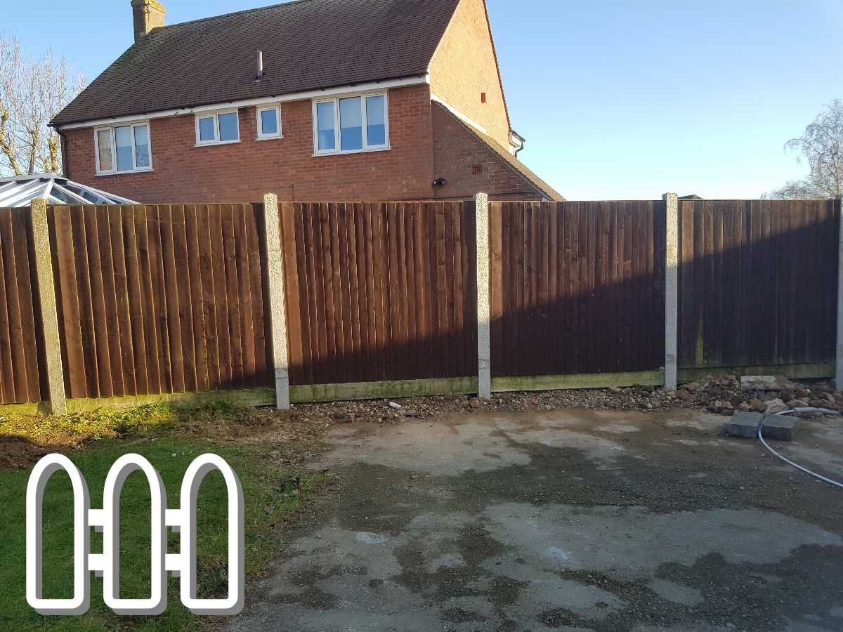 A sturdy brown wooden fence recently installed outside a brick house with clear skies