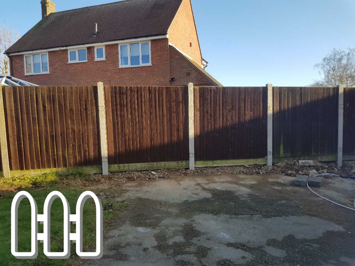 Sturdy dark brown wooden fence installed beside a house, creating privacy and security, under clear blue sky