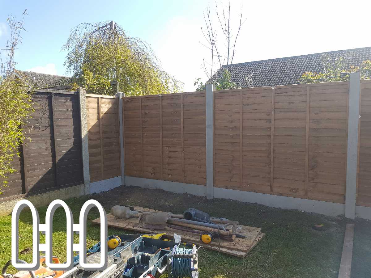 Newly installed wooden fence in a backyard, with tools and construction equipment scattered in the foreground under bright sunlight.