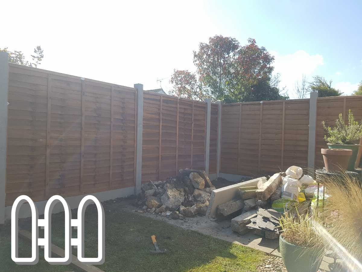 Newly installed wooden fence in a sunny backyard with construction materials and tools scattered around