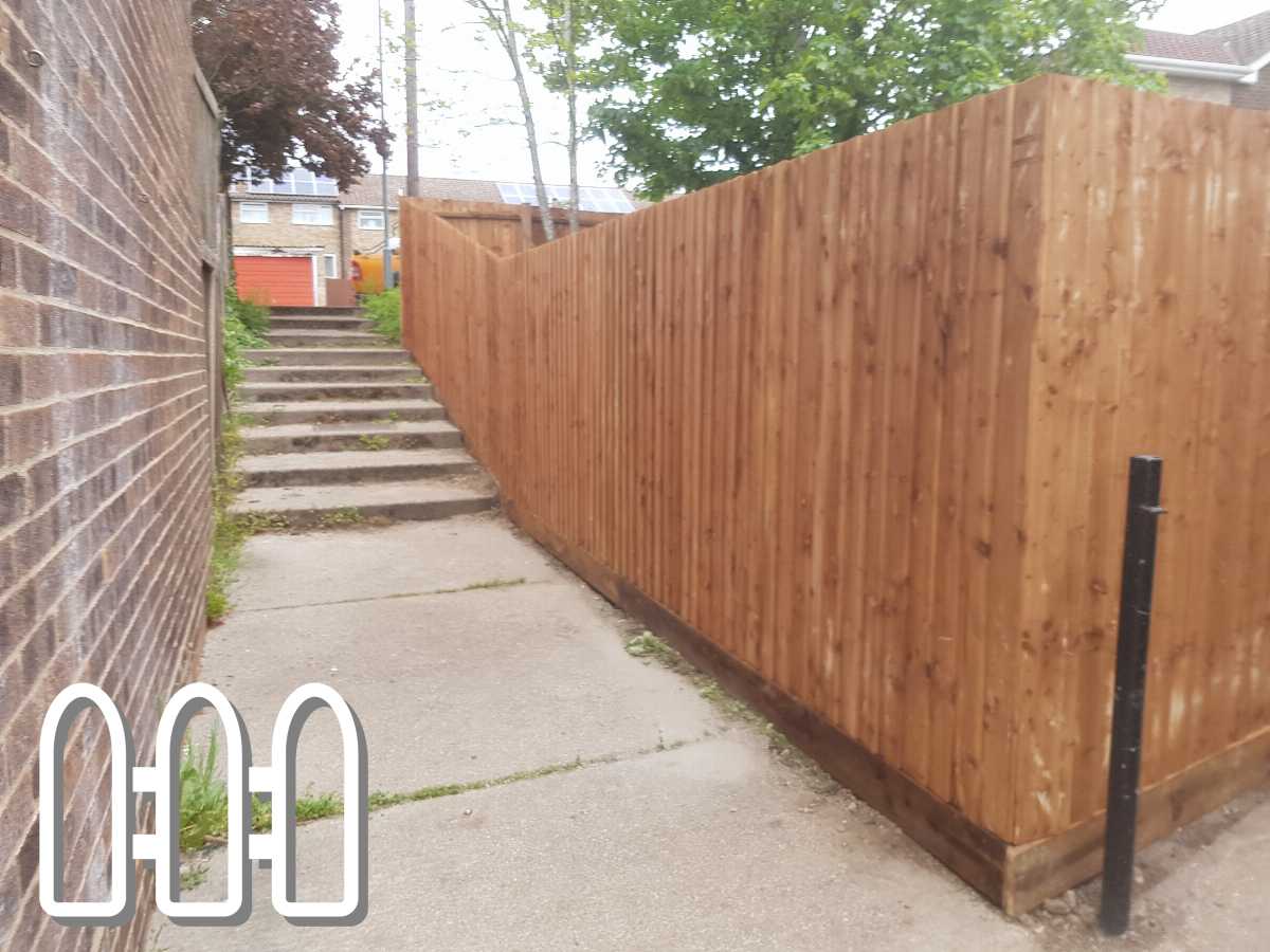 Newly installed wooden fence along a residential pathway with concrete steps leading up to houses