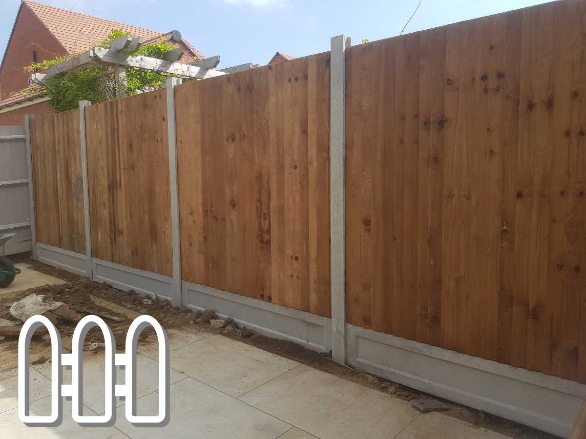 Wooden fence panels mounted on concrete posts, lining a residential backyard with visible stone tiled pavement.