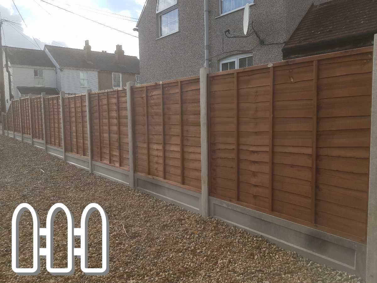 Long straight wooden fence with concrete posts installed along a gravel path beside a house