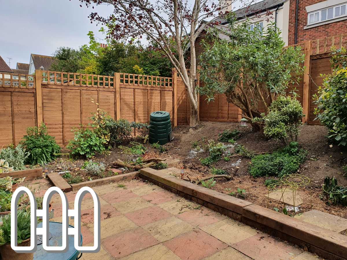A newly renovated backyard garden featuring a high wooden fence, various plants and shrubs, and a brick patio area