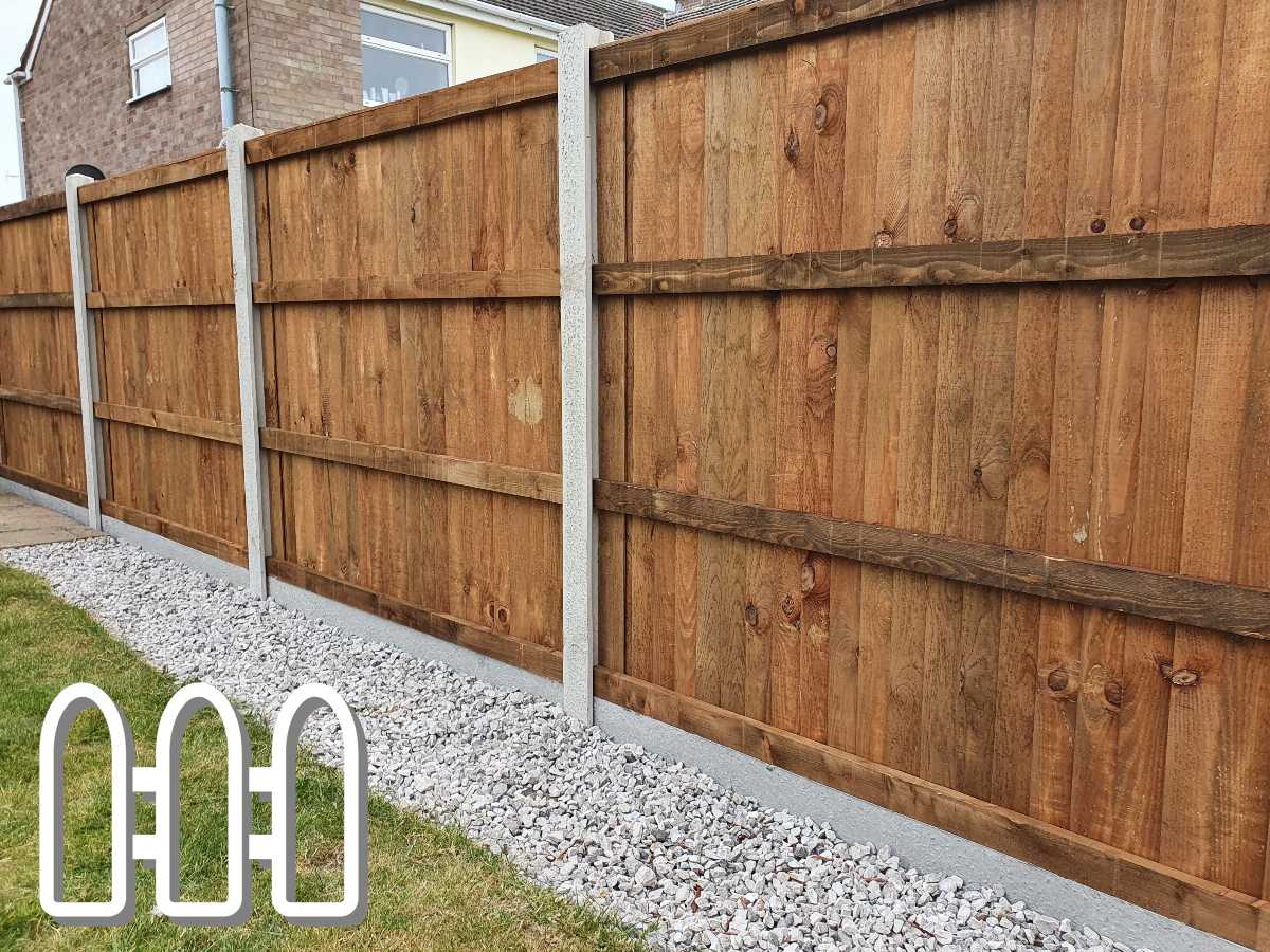 Sturdy brown wooden fence with vertical panels and concrete posts installed in a residential area, bordered by a strip of white gravel